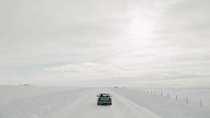 銀色小型貨車在雪路上行駛，穿越冰凍的沙漠景觀。 — 天空 壁紙