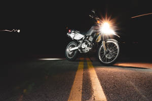夜間黑暗道路上帶有明亮頭燈的銀色摩托車，帶有動態模糊效果。 — 改裝摩托車 壁紙