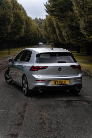 銀色福斯 Golf GTI 停放在潮濕的道路上，周圍有樹木。 — 高爾夫球場 壁紙