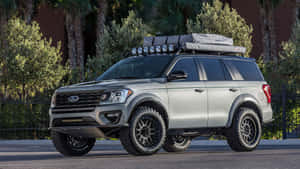 銀色福特Explorer SUV，配備越野輪胎和車頂行李架，停放在戶外。 — 福特 壁紙