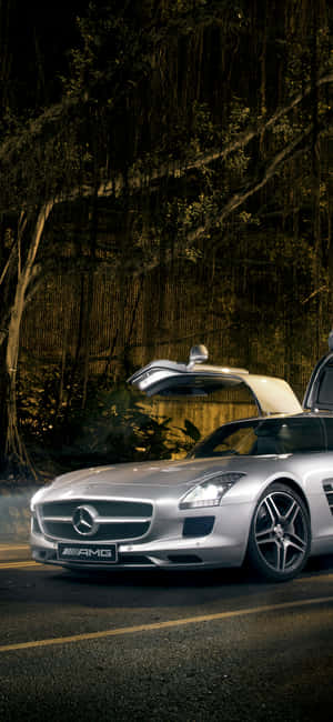銀色賓士AMG SLS，鷗翼車門打開，在夜晚的黑暗森林道路上。 — iPhone 18 Pro Max 壁紙