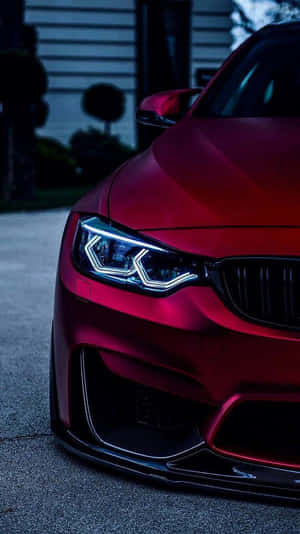 紅色BMW跑車，車頭燈亮起，夜間停泊。 — BMW iPhone 壁紙