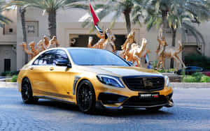 金色Brabus Rocket 900轎車停在沙漠主題雕像和棕櫚樹附近。 — Mercedes Benz C300 壁紙