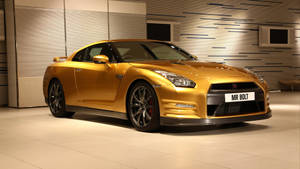 金色日產GT-R跑車在時尚現代的展廳中展示。 — 日產 Skyline GTR R34 壁紙