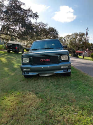 青綠色的GMC pickup truck停泊在草地上，背景有樹木和藍天。 — Kindle 壁紙