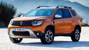 橙色Dacia Duster SUV停泊在碎石上，靠近山脈 — 高清汽車 壁紙