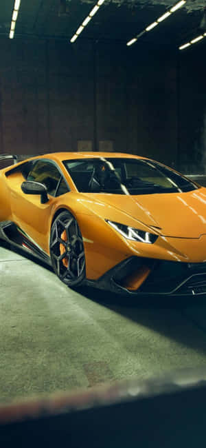 螢光燈下的混凝土車庫中的橙色藍寶堅尼 Huracán。 — iPhone 18 Pro Max 壁紙