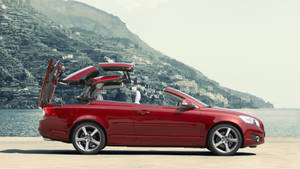 紅色敞篷車，車門打開，停泊在湖邊，背景有山丘村莊。 — Mercedes Benz C300 壁紙