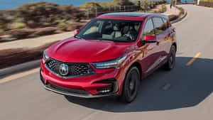 紅色Acura SUV在海岸公路上行駛，背景模糊。 — Acura 壁紙