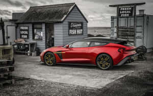 紅色Aston Martin Vanquish S停泊在海邊碎石停車場的魚棚附近。 — 阿斯頓維拉 壁紙