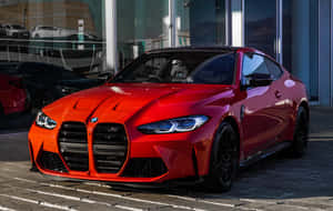 日落時分，紅色BMW M4跑車停在玻璃建築外。 — 日落 壁紙