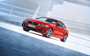 紅色BMW雙門跑車在藍色水邊的白色賽道上飛馳。 — KTM 摩托車 壁紙