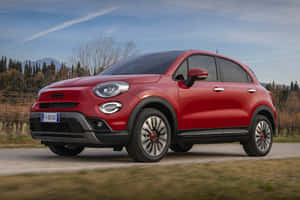 紅色Fiat 500X SUV在鄉村道路上行駛，背景有山脈。 — 飛雅特 壁紙