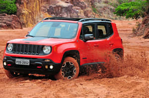 紅色Jeep Renegade在沙漠峽谷的紅色塵土中行駛。 — Surface Pro 壁紙
