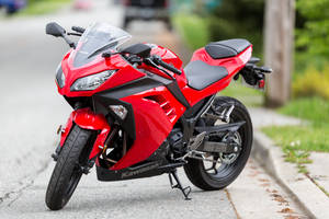 紅色Kawasaki跑車摩托車停在路邊草地旁。 — 改裝摩托車 壁紙