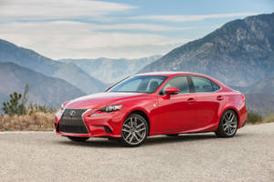 紅色Lexus房車停在碎石路上，背景是日落時分的山脈。 — 凌志 壁紙