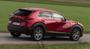 紅色Mazda CX-30 SUV在鄉村道路上行駛，伴有綠色田野。 — 馬自達 壁紙