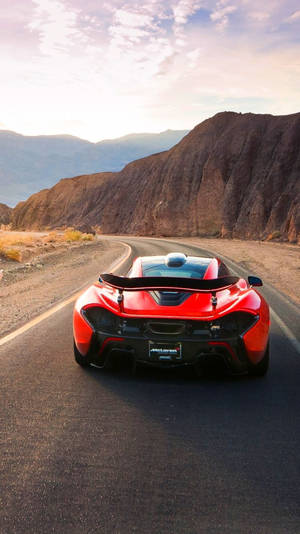 紅色McLaren跑車在日落時分行駛在沙漠山路上。 — 麥拉倫 壁紙