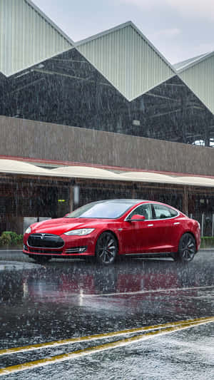 紅色Tesla汽車在雨中停在濕漉漉的城市街道上，靠近工業建築。 — 特斯拉 壁紙