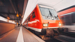一輛紅色火車在現代化車站中高速行駛，帶有動態模糊效果。 — 地鐵 壁紙