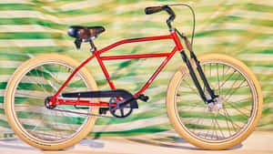 一輛紅色自行車配奶油色輪胎，背景為綠白條紋。 — Studio Display 壁紙