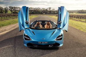 藍色McLaren 720S Spider在葡萄園道路上開門，日落時分。 — 4K 法拉利 壁紙