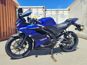 藍色Yamaha R15運動機車停放在室外貨櫃附近。 — 4:3 壁紙