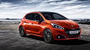 橙色Peugeot 208停泊在瀝青路上，背景為多雲天空。 — 標緻 壁紙