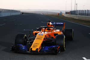 日落時分，賽道上的一輛橙色和藍色一級方程式賽車。 — F1 2019 壁紙