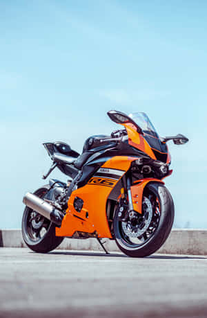 橙色和黑色Yamaha R6運動摩托車停在藍天下的人行道上。 — 榮耀MagicPad4 壁紙