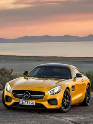 黃色 Mercedes-AMG GT 停泊在日落時分的湖邊，背景有山巒。 — Mercedes Benz C300 壁紙