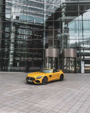 黃色敞篷跑車停放在玻璃建築前 — Mercedes Amg iPhone 壁紙