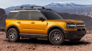 黃色福特Bronco SUV停泊在沙漠中，背景有山脈 — 老福特卡車 壁紙