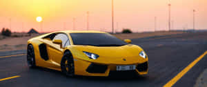 黃色藍寶堅尼 Aventador 在日落時分於沙漠公路上飛馳。 — 3440x1440 壁紙