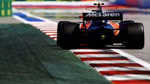 麥拉倫F1賽車在設有紅、白、綠色路緣石的賽道上疾馳。 — 賽車 壁紙