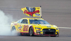 黃色NASCAR賽車以煙霧和旗幟慶祝冠軍。 — 賽車 壁紙