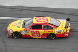 黃色和紅色的 NASCAR 賽車在賽道上疾馳，帶有動態模糊效果。 — 賽車 壁紙