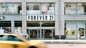 黃色的士高速駛過一間帶有特價標誌的Forever 21零售店。 — 永遠21 壁紙