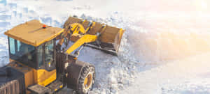 黃色除雪推土機在明亮的冬日陽光下清理積雪。 — 超寬 GIF 壁紙