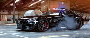 黑色 Mercedes-AMG GT R 在倉庫內甩尾，伴有煙霧和警燈。 — 2560x1080 壁紙