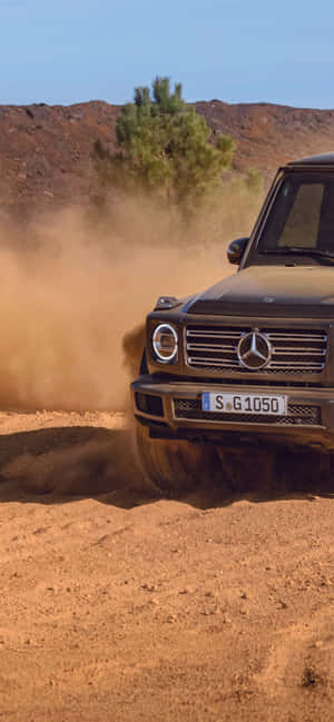 黑色 Mercedes G-Class 在沙漠地形上行駛，揚起沙塵。 — Galaxy A55 壁紙