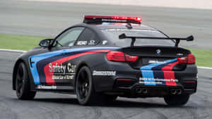 黑色BMW M4安全車，紅藍白塗裝，在賽道上閃爍紅燈。 — 賽車 壁紙
