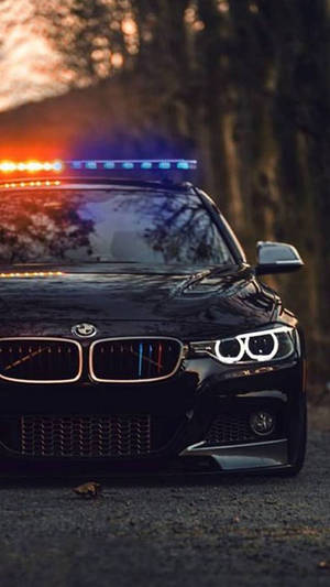 黃昏時停泊在樹林地區的黑色警車，帶有閃爍燈光。 — 警察 GIF 壁紙