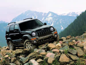 黑色Jeep Liberty在山地森林景觀中的岩石上行駛。 — 吉普 壁紙