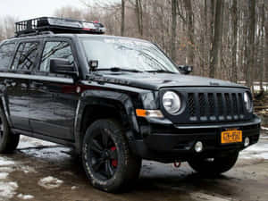黑色Jeep Patriot停在雪地森林中，周圍有光禿禿的樹木。 — 吉普 壁紙