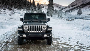 黑色Jeep Wrangler停放在白雪覆蓋的山路上，周圍有常青樹 — 吉普 壁紙