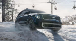黑色Kia SUV在雪中行駛，上方有滑雪纜車。 — 起亞 壁紙