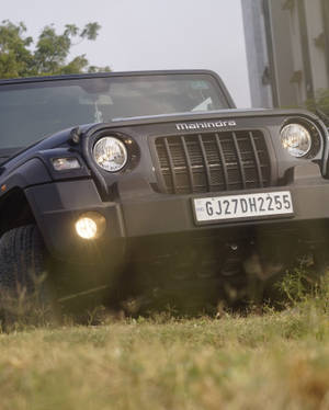 黑色Mahindra Thar SUV停在草地上，車頭燈亮起。 — 草地 壁紙