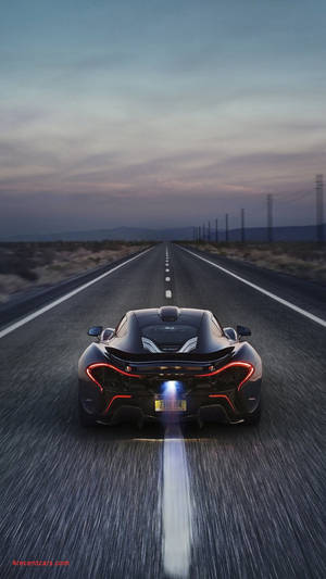 黑色McLaren在黃昏時分沿沙漠高速公路奔馳，尾燈發紅光。 — 好看汽車 壁紙