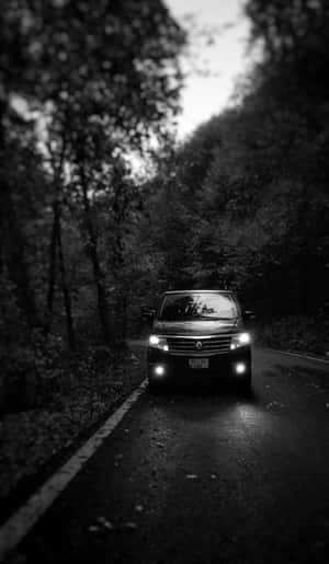 黑色SUV車頭燈照亮夜間森林道路。 — Tecno Megapad 壁紙